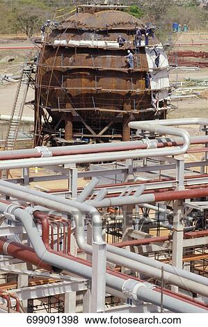 Stock Photo - Construction workers working at under construction oil refinery. Fotosearch