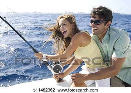 Stock Image - Couple sitting in a boat and fishing. Fotosearch
