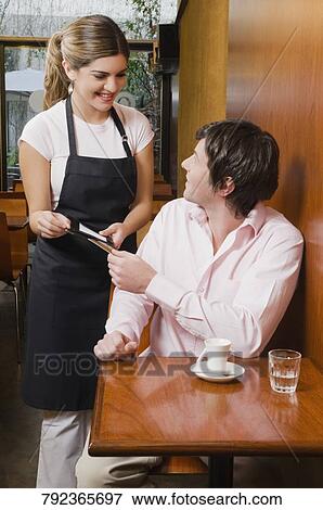 Stock Photo - Customer paying his bill to a waitress. Fotosearch