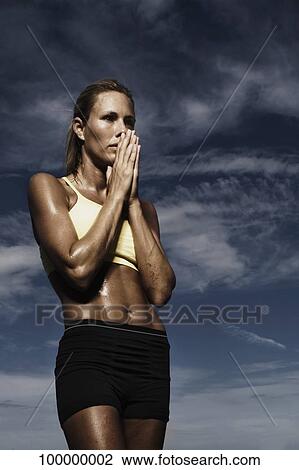 Female athlete standing with her hands folded View Large Photo Image Stock Image - Female athlete standing with her hands folded. Fotosearch