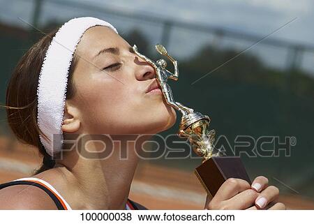 Stock Photo - Female tennis player kissing a trophy. Fotosearch