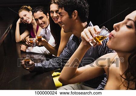 Five friends sitting at a bar counter and drinking whiskey View Large Photo Image Picture - Five friends sitting at a bar counter and drinking whiskey. Fotosearch