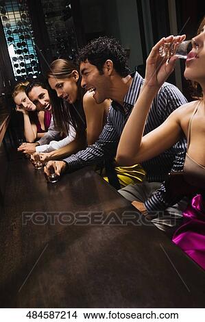Five friends sitting at a bar counter and drinking whiskey View Large Photo Image Picture - Five friends sitting at a bar counter and drinking whiskey. Fotosearch