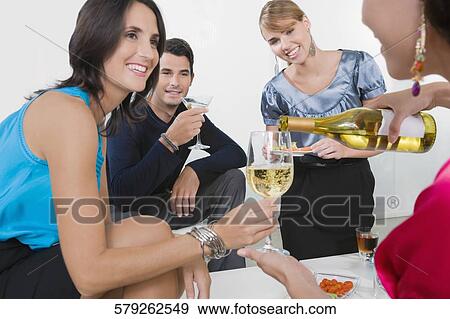 Stock Photo - Four friends celebrating with wine and cocktail. Fotosearch