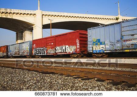 Freight train passing under a bridge View Large Photo Image Stock Image - Freight train passing under a bridge. Fotosearch