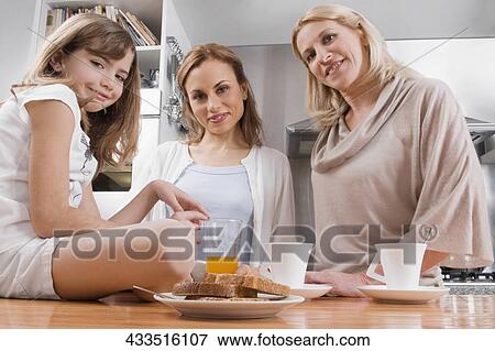 Stock Photo - Girl having breakfast with her mother and grandmother. Fotosearch