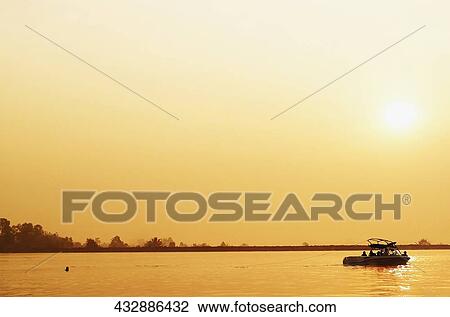 Stock Image - Group of people in a boat at sunset, Chiang Rai, Amphoe Mueang, Chiang Rai Province, Thailand. Fotosearch