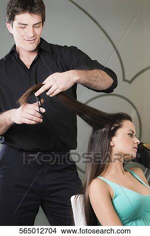 Hairdresser cutting the hair of a young woman View Large Photo Image Picture - Hairdresser cutting the hair of a young woman. Fotosearch