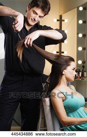 Hairdresser cutting the hair of a young woman View Large Photo Image Stock Photograph - Hairdresser cutting the hair of a young woman. Fotosearch