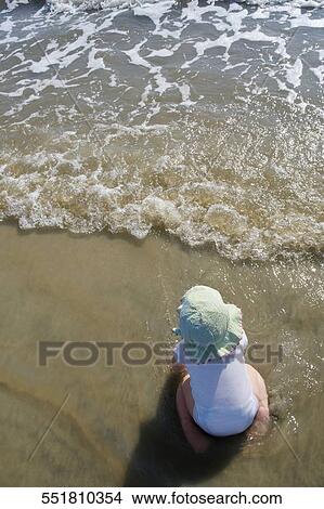High angle view of a baby girl kneeling on the beach View Large Photo Image Picture - High angle view of a baby girl kneeling on the beach. Fotosearch
