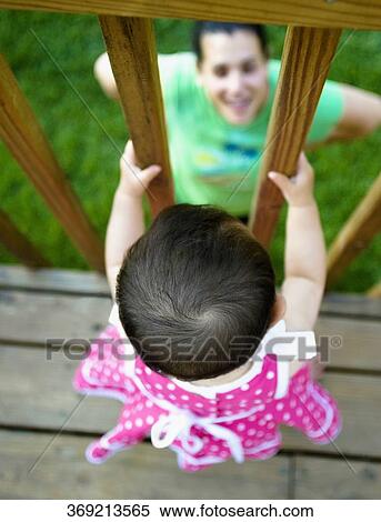 High angle view of a baby girl standing in the balcony and her mother looking at her View Large Photo Image Stock Photography - High angle view of a baby girl standing in the balcony and her mother looking at her. Fotosearch