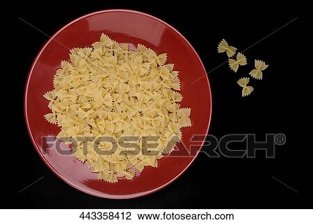 Stock Image - High angle view of a bowl of raw bow tie pasta. Fotosearch