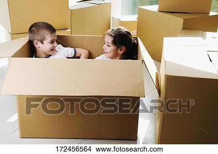 Picture - High angle view of a boy and a girl smiling in a cardboard box. Fotosearch