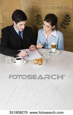 High angle view of a businessman and a businesswoman discussing in a cafe View Large Photo Image Stock Photo - High angle view of a businessman and a businesswoman discussing in a cafe. Fotosearch