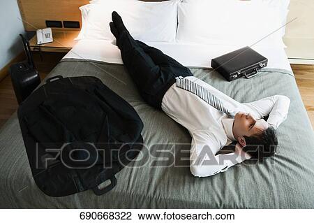 High angle view of a businessman resting on the bed with his hands behind his head View Large Photo Image Stock Image - High angle view of a businessman resting on the bed with his hands behind his head. Fotosearch
