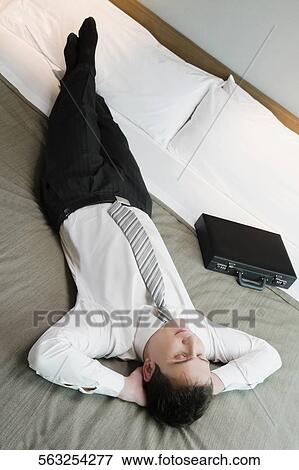High angle view of a businessman sleeping on the bed View Large Photo Image Stock Photo - High angle view of a businessman sleeping on the bed. Fotosearch