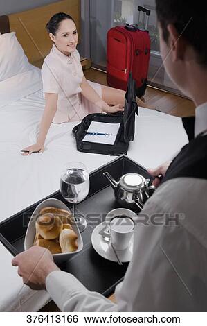 High angle view of a businesswoman sitting on the bed and a waiter serving breakfast View Large Photo Image Stock Photograph - High angle view of a businesswoman sitting on the bed and a waiter serving breakfast. Fotosearch