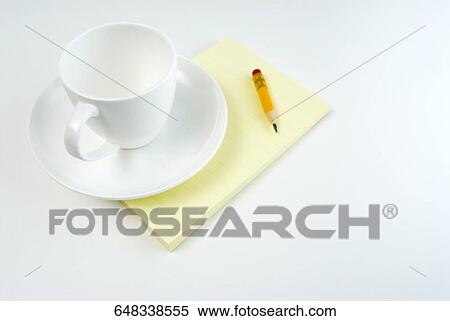 Stock Photography - High angle view of a cup and a saucer on a notepad. Fotosearch