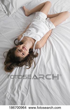 High angle view of a girl lying on the bed and smiling View Large Photo Image Picture - High angle view of a girl lying on the bed and smiling. Fotosearch