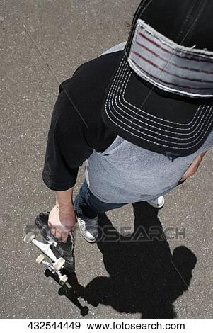 High angle view of a man holding a skateboard View Large Photo Image Stock Photo - High angle view of a man holding a skateboard. Fotosearch