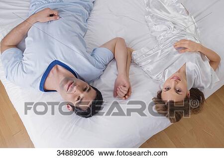Stock Photograph - High angle view of a mid adult couple lying on a mattress. Fotosearch