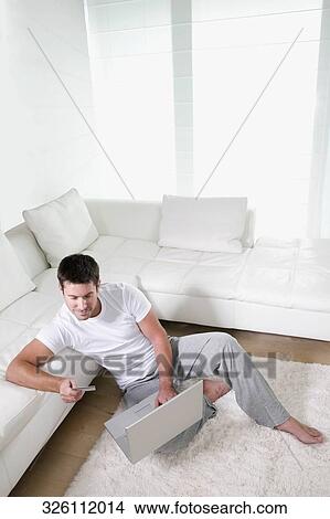 High angle view of a mid adult man holding a credit card and using a laptop View Large Photo Image Picture - High angle view of a mid adult man holding a credit card and using a laptop. Fotosearch