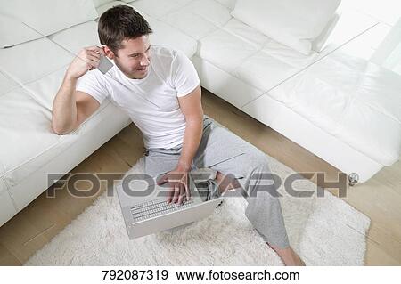High angle view of a mid adult man holding a credit card and using a laptop View Large Photo Image Stock Photo - High angle view of a mid adult man holding a credit card and using a laptop. Fotosearch