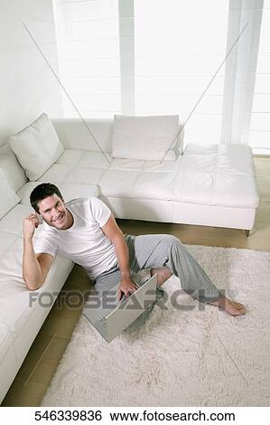 Stock Photograph - High angle view of a mid adult man holding a credit card and using a laptop. Fotosearch