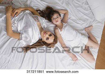 High angle view of a mid adult woman lying on the bed with her daughter View Large Photo Image Stock Image - High angle view of a mid adult woman lying on the bed with her daughter. Fotosearch