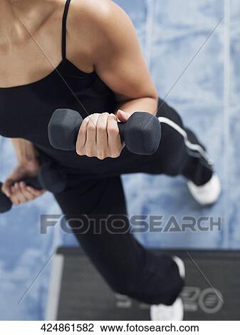 High angle view of a mid adult woman exercising with dumbbells View Large Photo Image Stock Image - High angle view of a mid adult woman exercising with dumbbells. Fotosearch