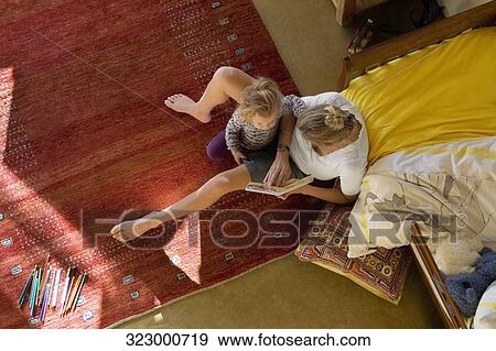 Stock Photo - High angle view of a mid adult woman teaching her daughter. Fotosearch