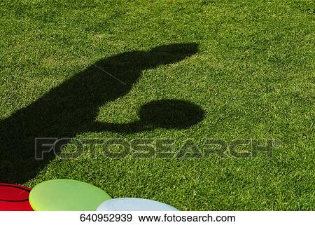 Stock Photo - High angle view of a shadow of a person holding a plastic disc. Fotosearch