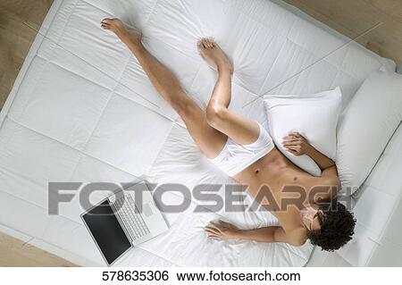 High angle view of a young man lying on the bed View Large Photo Image Stock Photograph - High angle view of a young man lying on the bed. Fotosearch