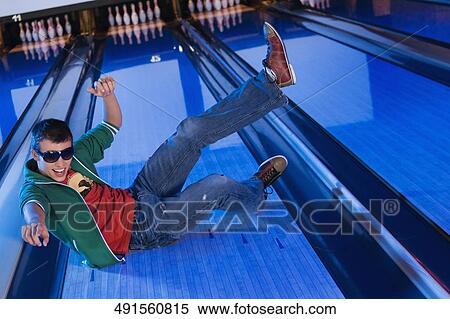 Stock Photography - High angle view of a young man sliding in a bowling alley. Fotosearch