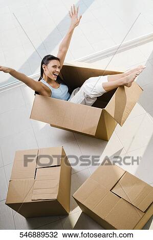 High angle view of a young woman laughing in a cardboard box View Large Photo Image Stock Image - High angle view of a young woman laughing in a cardboard box. Fotosearch