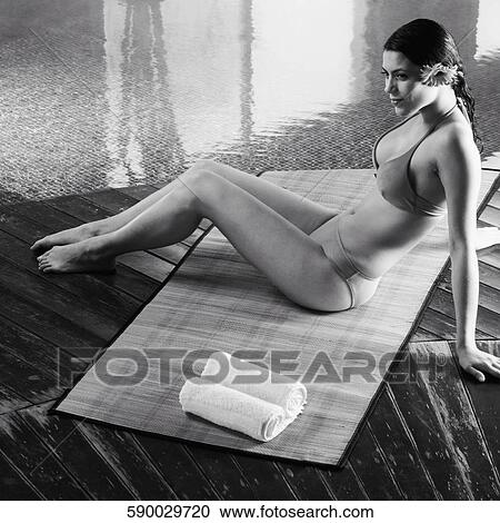 High angle view of a young woman sitting at the poolside View Large Photo Image Stock Image - High angle view of a young woman sitting at the poolside. Fotosearch