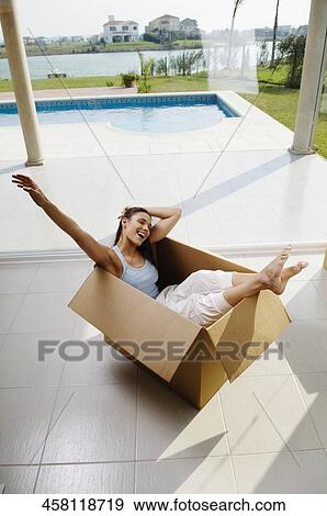 Stock Photo - High angle view of a young woman laughing in a cardboard box. Fotosearch