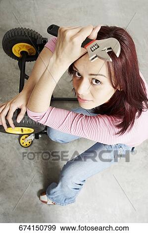 High angle view of a young woman holding a wrench View Large Photo Image Stock Photo - High angle view of a young woman holding a wrench. Fotosearch