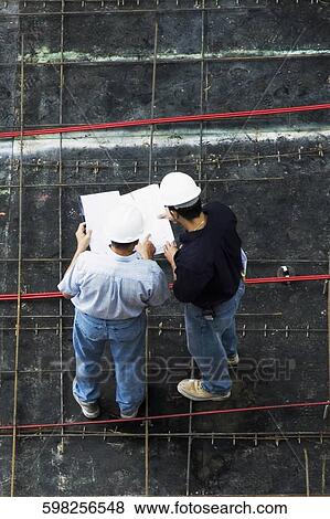 High angle view of two architects standing at a construction site View Large Photo Image Stock Photo - High angle view of two architects standing at a construction site. Fotosearch