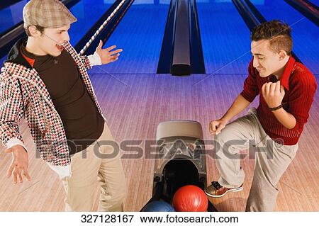 Stock Photo - High angle view of two young men standing in a bowling alley. Fotosearch