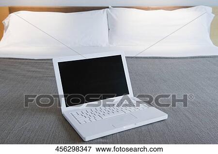 Laptop on the bed in a hotel room View Large Photo Image Stock Photo - Laptop on the bed in a hotel room. Fotosearch