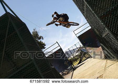 Stock Image - Low angle view of a BMX cyclist performing in mid-air. Fotosearch