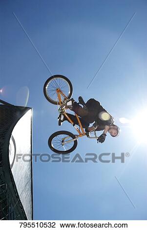 Low angle view of a BMX cyclist performing in mid-air View Large Photo Image Stock Image - Low angle view of a BMX cyclist performing in mid-air. Fotosearch