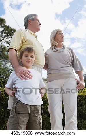 Low angle view of a boy standing with his grandparents in a park View Large Photo Image Stock Photo - Low angle view of a boy standing with his grandparents in a park. Fotosearch
