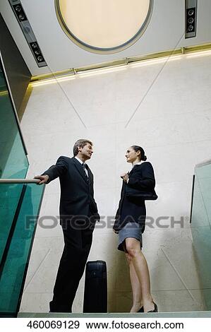 Stock Photo - Low angle view of a businessman and a businesswoman standing together and talking. Fotosearch