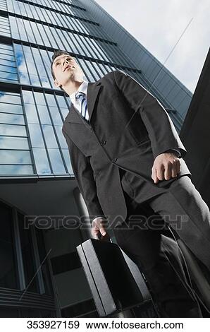 Stock Photo - Low angle view of a businessman holding a briefcase. Fotosearch