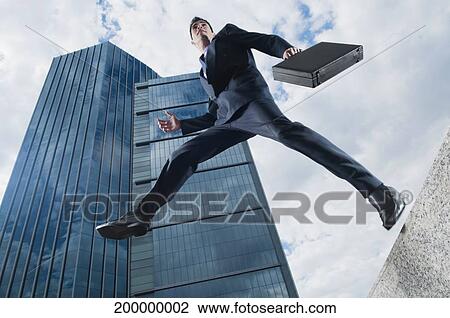 Low angle view of a businessman jumping in air View Large Photo Image Stock Image - Low angle view of a businessman jumping in air. Fotosearch