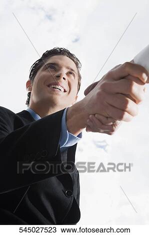 Low angle view of a businessman shaking hand with another businessman View Large Photo Image Stock Image - Low angle view of a businessman shaking hand with another businessman. Fotosearch