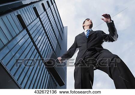 Low angle view of a businessman carrying a briefcase View Large Photo Image Stock Photograph - Low angle view of a businessman carrying a briefcase. Fotosearch