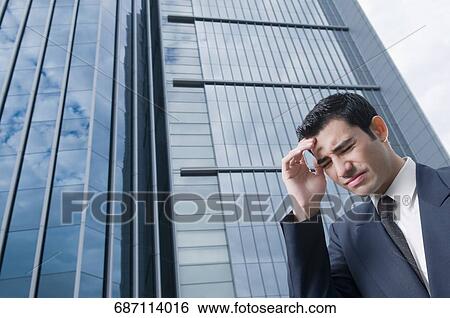 Low angle view of a businessman suffering from a headache View Large Photo Image Stock Photograph - Low angle view of a businessman suffering from a headache. Fotosearch
